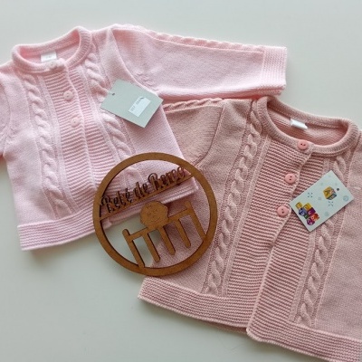 Casacos bebé rosa claro e rosa com padrão de trança e botões, etiquetas e placa em madeira