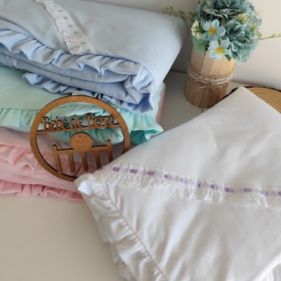 Mantinhas de bebé em algodão e renda com cores suaves e arranjo floral decorativo