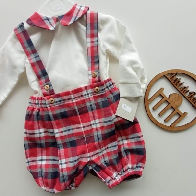 Conjunto de bebé com camisa branca e calções xadrez com alças sobre superfície branca