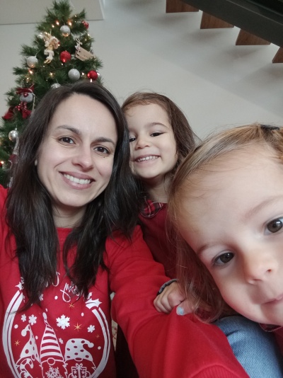 Mulher e crianças com roupa vermelha em frente a árvore de Natal decorada