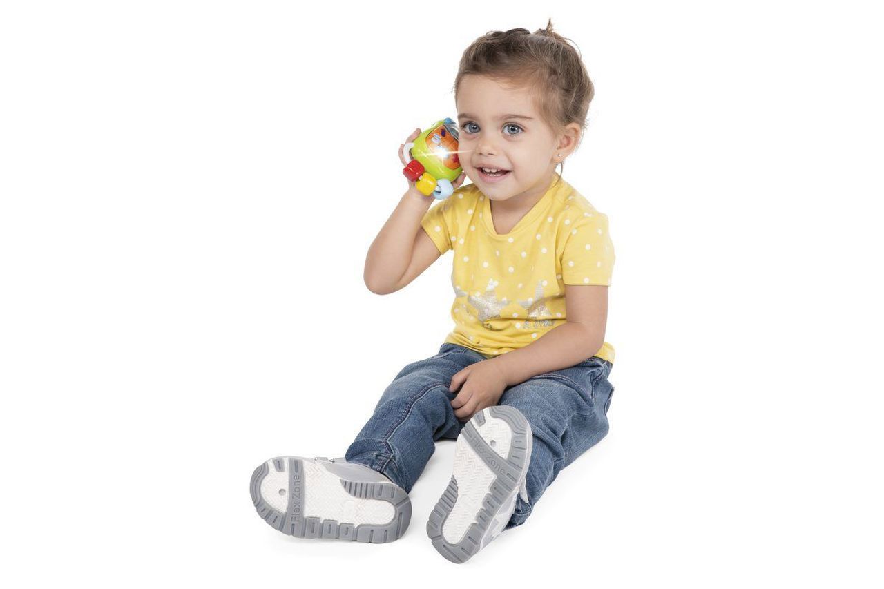 Criança sentada com roupa amarela e azul segurando brinquedo colorido