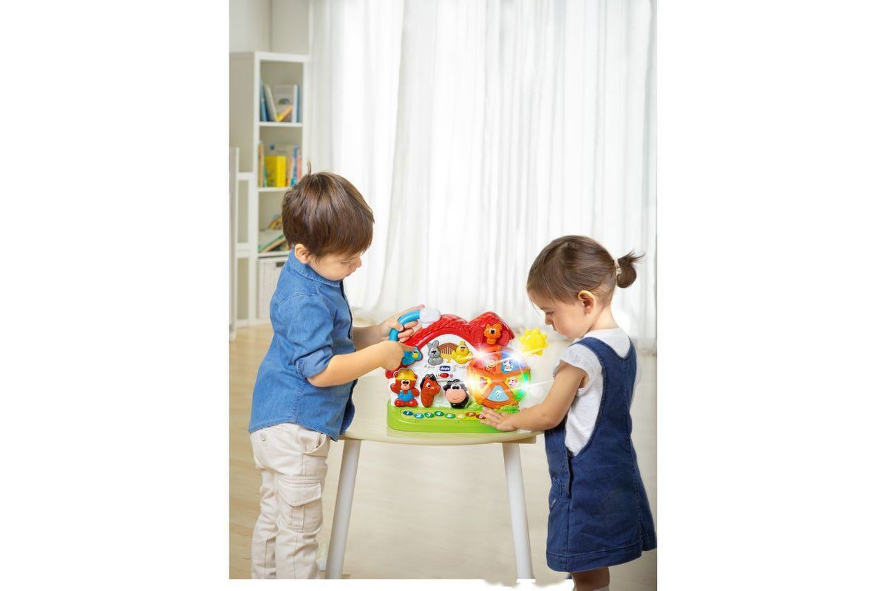 Crianças a brincar com uma mesa de atividade colorida num quarto claro