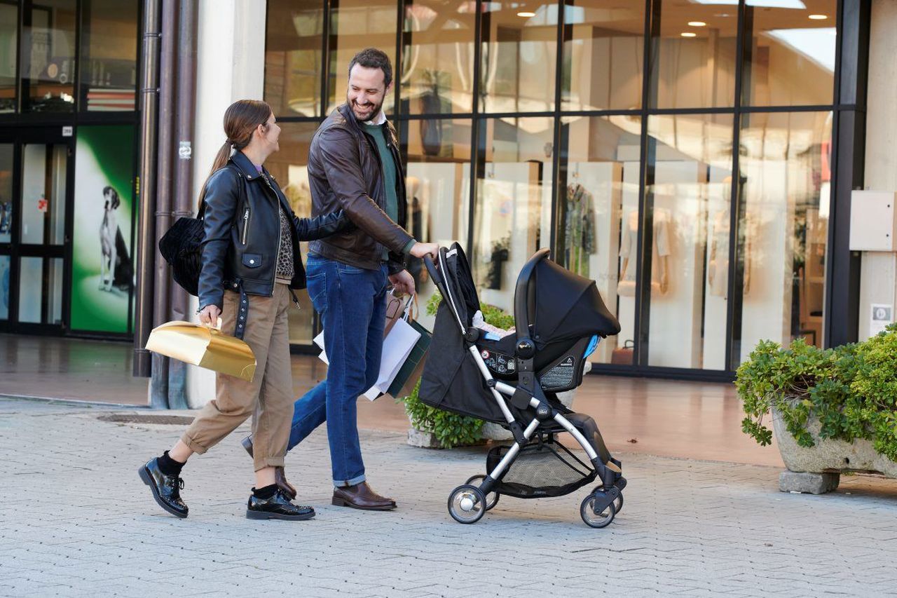 Casal a passear com carrinho de bebé preto em zona urbana