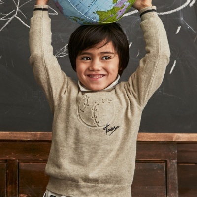 Camisola bege com bordado e assinatura 'Funy' usada por criança com globo na cabeça