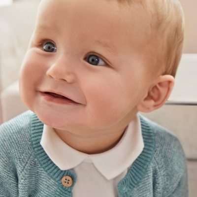 Bebé com casaco de malha azul e camisa branca colarinho