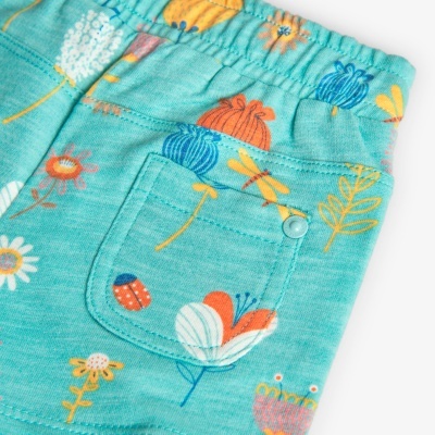 Calças azuis com padrão de flores e insetos coloridos e bolso traseiro com botão