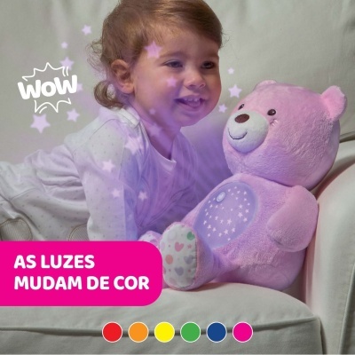 Criança de pijama branco com ursinho de pelúcia cor-de-rosa com luzes coloridas