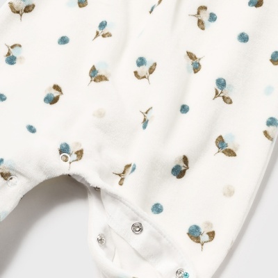 Pijama de bebé branco com padrão de pequenas flores azuis e castanhas e botões de pressão metálicos.