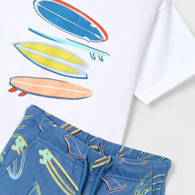 Conjunto infantil com t-shirt branca com estampa de pranchas e calças azuis com padrão de pranchas.