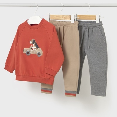 Conjunto roupa infantil com sweatshirt vermelha e duas calças bege e cinzenta penduradas