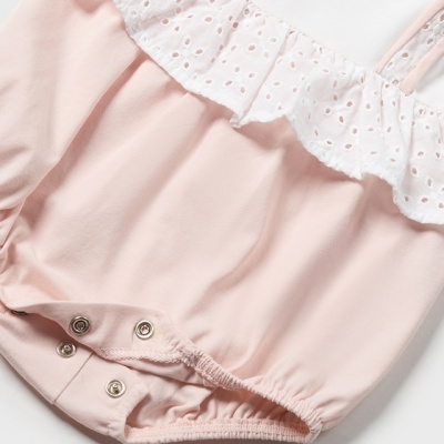 Body de bebé rosa claro com folho branco perfurado e botões de pressão.