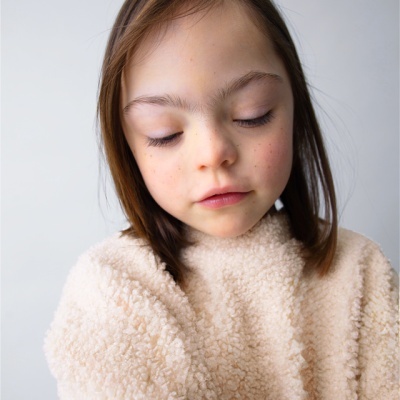 Menina com camisola felpuda bege e fundo branco
