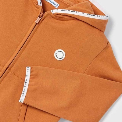 Casaco de criança cor ferrugem com capuz e fecho, detalhe texto GOOD MOOD nas bordas.