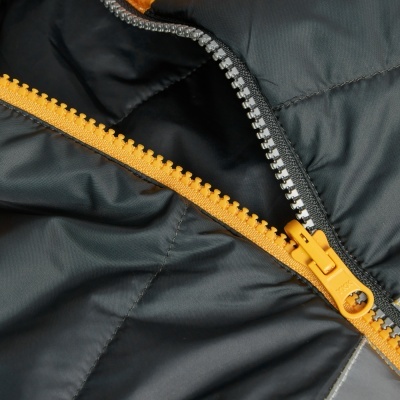 Fecho éclair amarelo e prateado em tecido acolchoado cinza escuro.