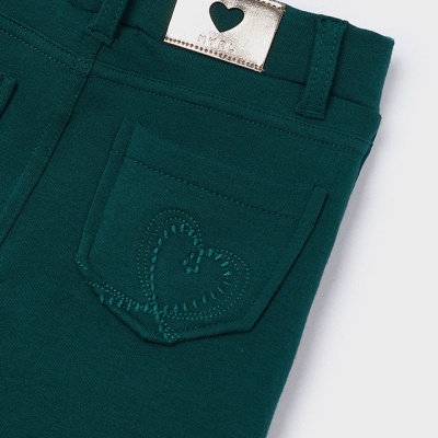 Calças verdes com bolso bordado em forma de coração e etiqueta metálica prateada.