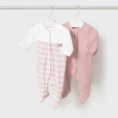 Dois macacões de bebé, um branco e rosa às riscas e outro rosa com estrelas bordadas.