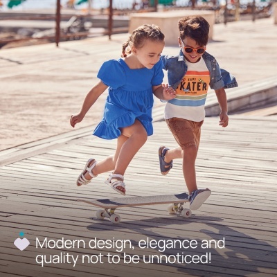 Duas crianças a andar em skate num passadiço de madeira junto à água