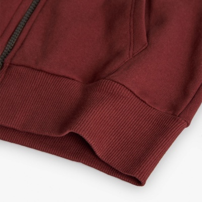 Detalhe de manga e parte inferior de camisola bordeaux com punho canelado