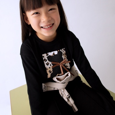 Camisola preta com estampa animal print e laço castanho numa rapariga sentada