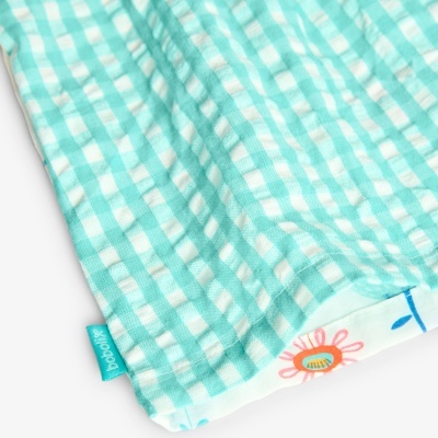 Pano azul-turquesa quadriculado com borda floral e etiqueta azul 'buba'