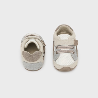 Sapatos de bebé bege e cinza com fecho de velcro sobre fundo branco
