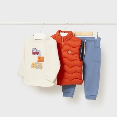 Conjunto de roupa infantil com camisola creme, colete laranja e calças azuis em cabides