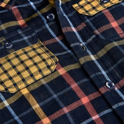 Camisa xadrez azul escuro com bolsos amarelos e botões azuis com texto