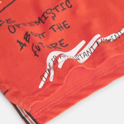 Detalhe de peça de roupa laranja com texto manuscrito e impresso