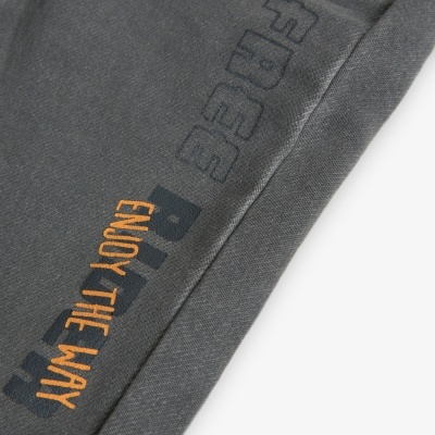 Detalhe de tecido cinza escuro com bordado colorido e texto estampado.