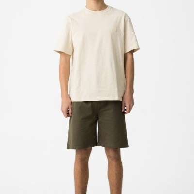 Pessoa com t-shirt bege, calções verde-oliva, meias pretas e sapatos pretos