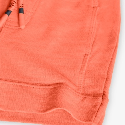 Parte inferior de peça de vestuário cor de salmão com cordões e bolso