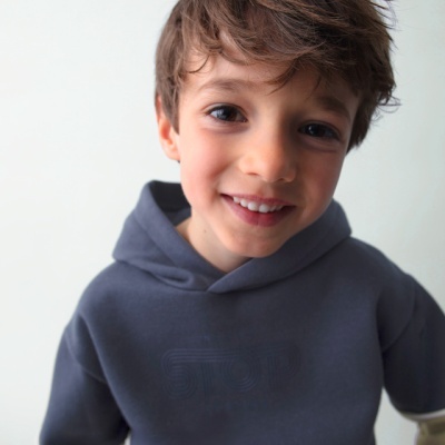 Criança com casaco com capuz cinzento escuro e mangas bege