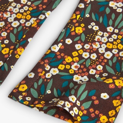 tecido estampado com flores amarelas, vermelhas e brancas, folhas verdes sobre fundo castanho