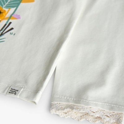 T-shirt branca com etiqueta e calça branca com renda na bainha em pano branco