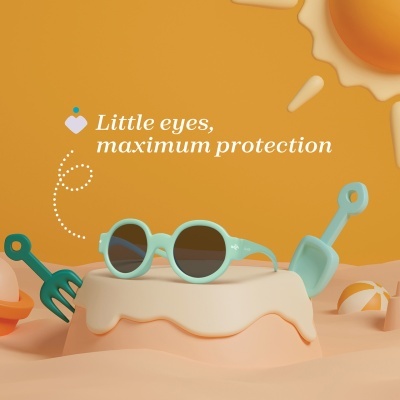 Óculos de sol para crianças azul claro sobre forma cremosa em ambiente amarelo com sol e acessórios de praia