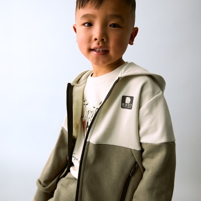 Criança com fato de treino verde e bege com fecho e logótipo WOLFY KIDS