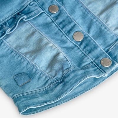 Casaco de ganga azul claro com botões metálicos e etiqueta azul