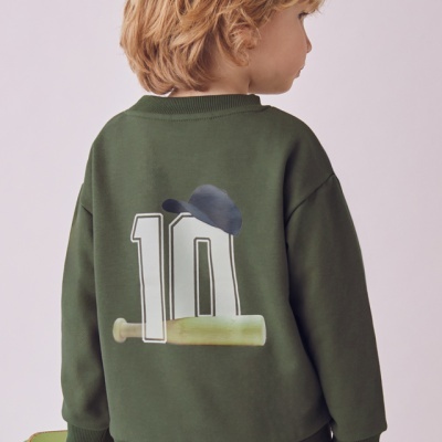 Criança vestindo sweatshirt verde escuro com número 10 e símbolos de basebol na parte de trás