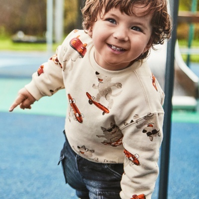 Criança em parque infantil vestindo camisola estampada e calças escuras