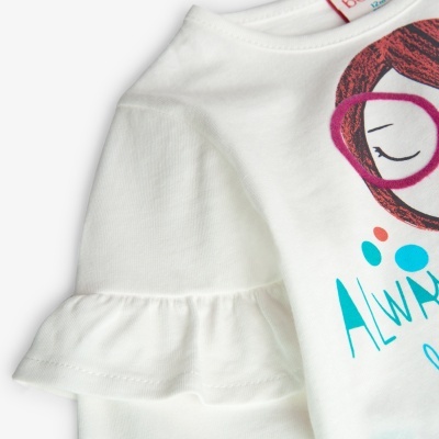 T-shirt branca com manga curta e estampa de rosto de rapariga, detalhe da manga com folho