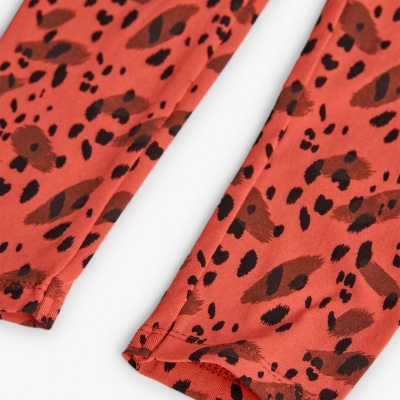 Pormenor de tecido vermelho com padrão de manchas castanho e preto