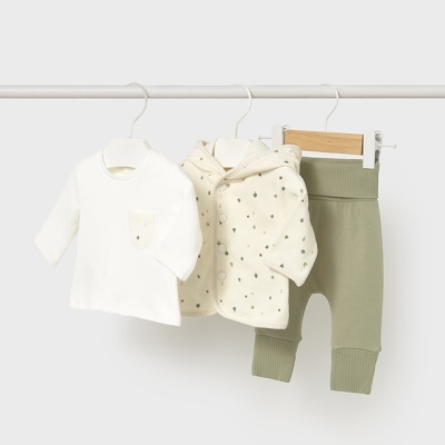 Conjunto de roupa de bebé com camisola branca, casaco creme com capuz e calças verdes pendurados.