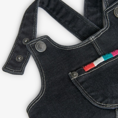 Roupagem preta com costuras e botão metálico, com bordado colorido