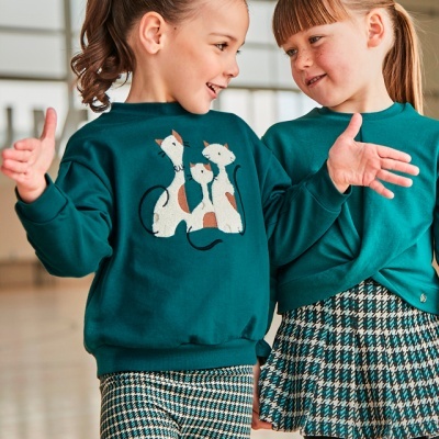 Duas meninas em ambiente interior com roupa azul-escura e padrão de gatos e riscas