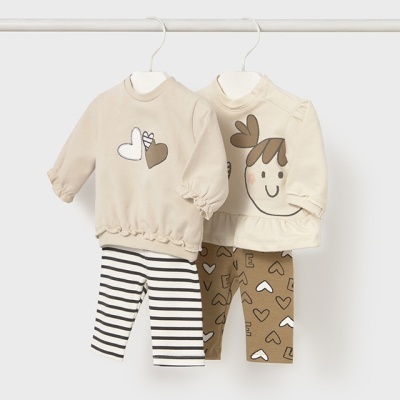 Dois conjuntos infantis bege com camisolas estampadas e calças padronizadas, pendurados em cabides.