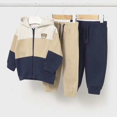 Conjunto de roupa infantil com casaco colorido e duas calças penduradas em cabides.