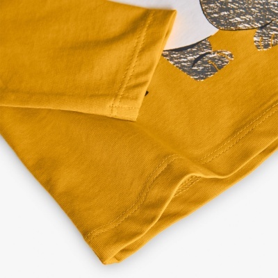 T-shirt amarela com estampa cinza e branco numa superfície branca