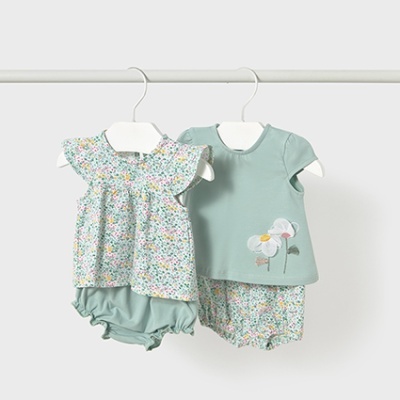 Dois conjuntos de bebé pendurados com blusa e calções em tons verdes e padrões florais.
