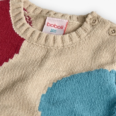 Roupa de bebé em malha bege com detalhes coloridos e etiqueta visível