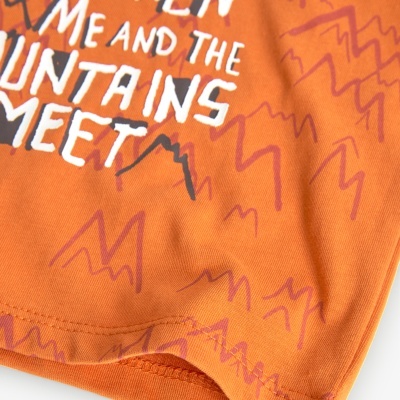 Detalhe de tecido laranja com padrão de montanhas e texto branco